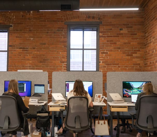 Three women working side by side at their desks