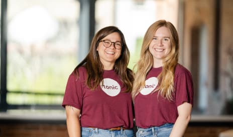 Two women wearing purple 'Tonic' shirts