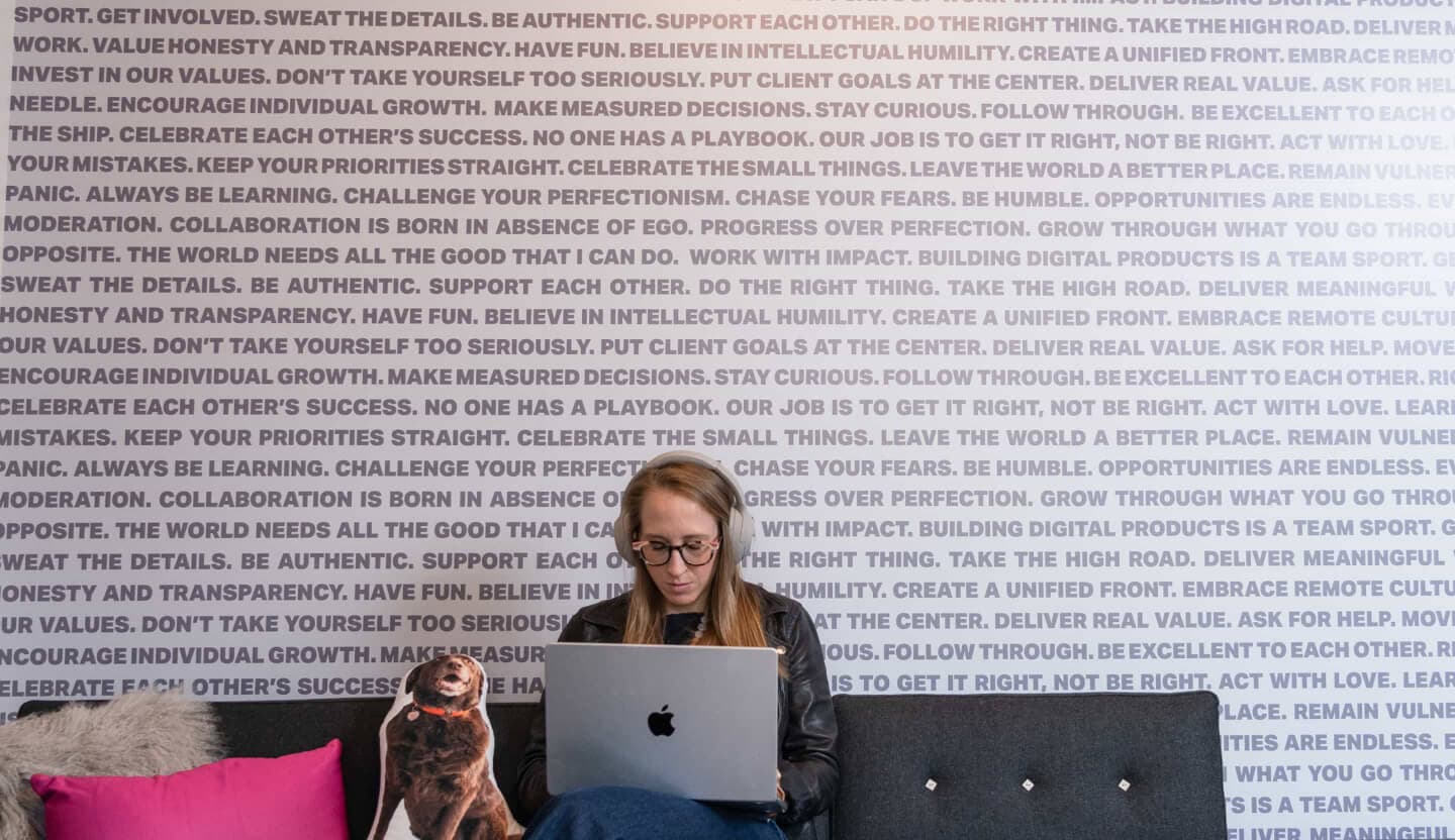 Strategist working on couch in front of company values wallpaper