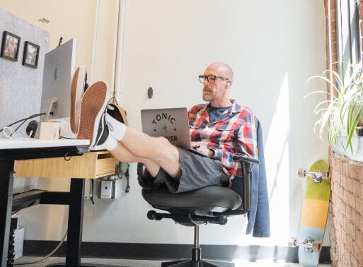 Developer working on laptop with his feet up on desk