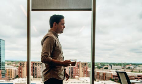 Profile of a man holding a cup of coffee with a view of the city behind him